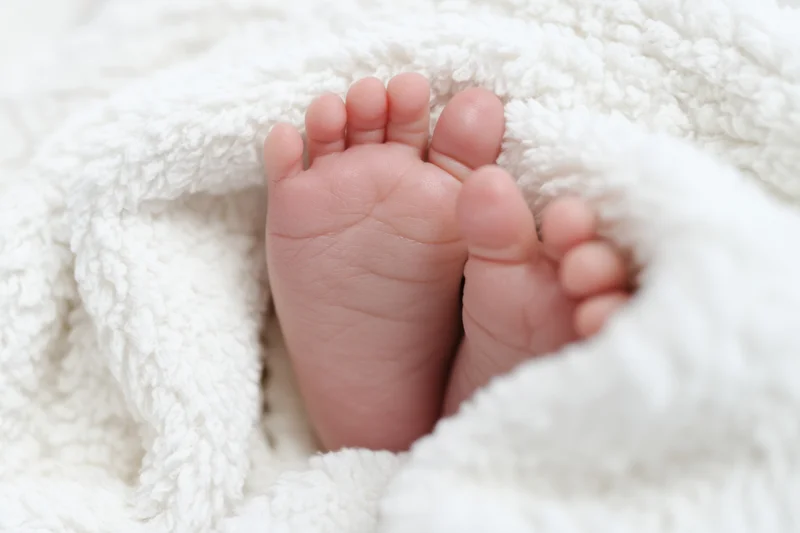 Baby's tiny feet resting on a fluffy white blanket