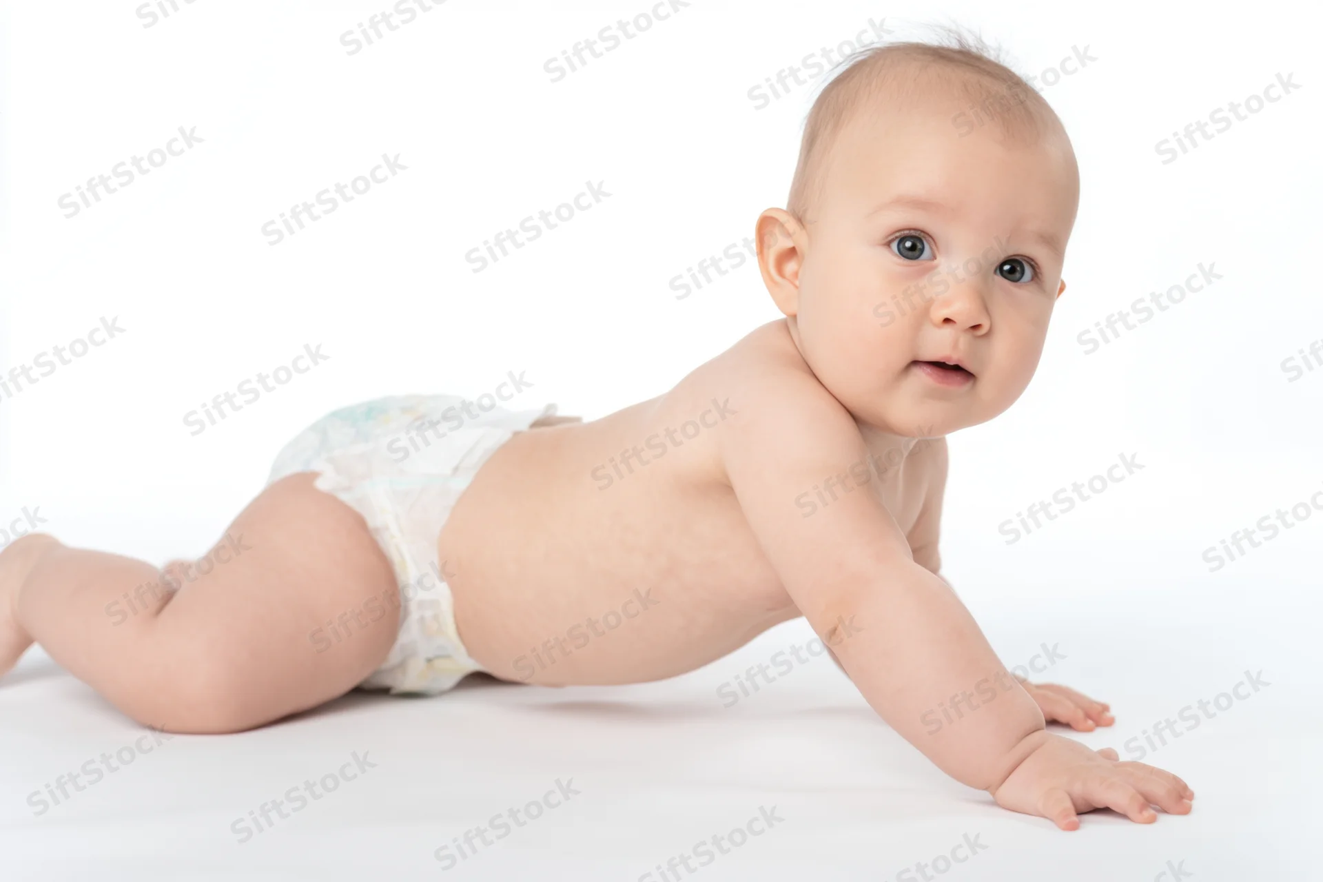 Baby in diaper crawling on white studio background