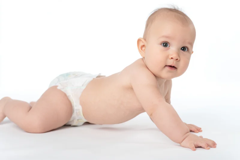 Baby in diaper crawling on white studio background