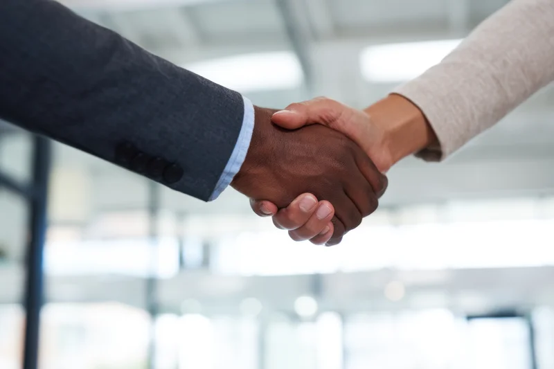 Close-up of two professionals shaking hands in a modern office interior
