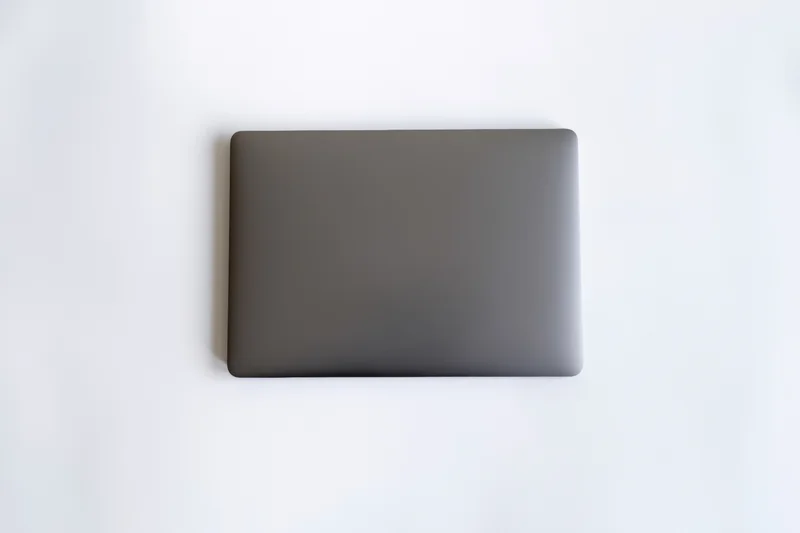 Closed dark gray laptop lid viewed from above on a clean white surface