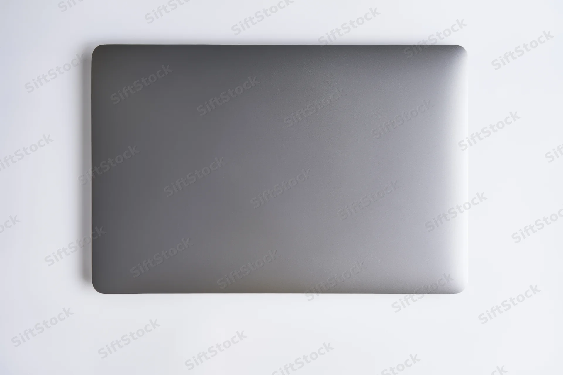 Closed dark gray laptop lid viewed from above on a plain white surface