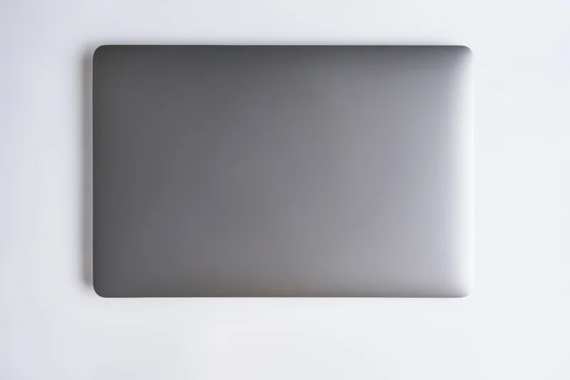 Closed dark gray laptop lid viewed from above on a plain white surface
