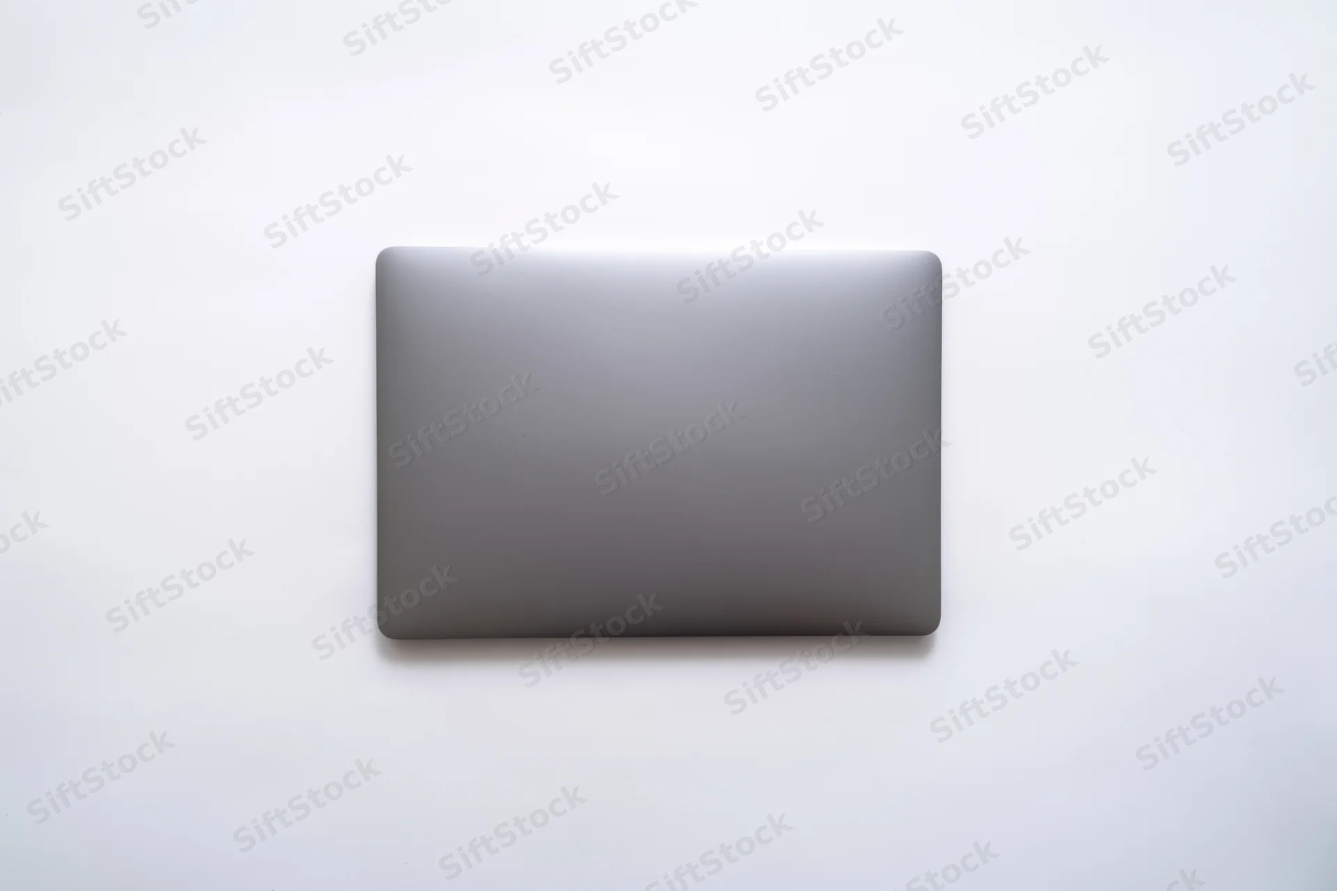 Closed dark gray laptop lid viewed from above on a plain white surface