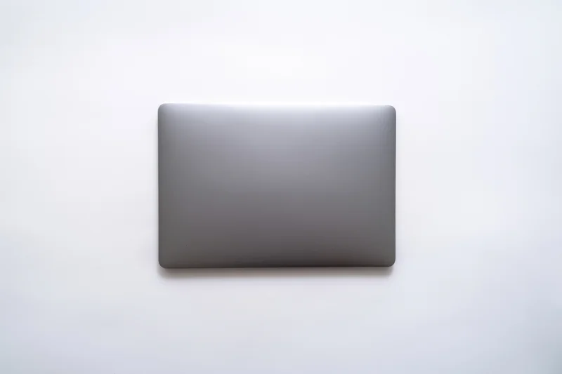 Closed dark gray laptop lid viewed from above on a plain white surface