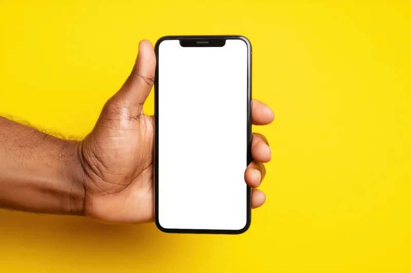 Hand holding smartphone with blank white screen against yellow background