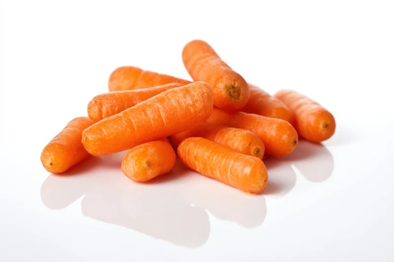 A small pile of bright orange baby carrots arranged on a clean white reflective surface
