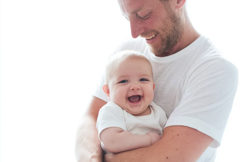 Father holding laughing baby in white t-shirt indoors