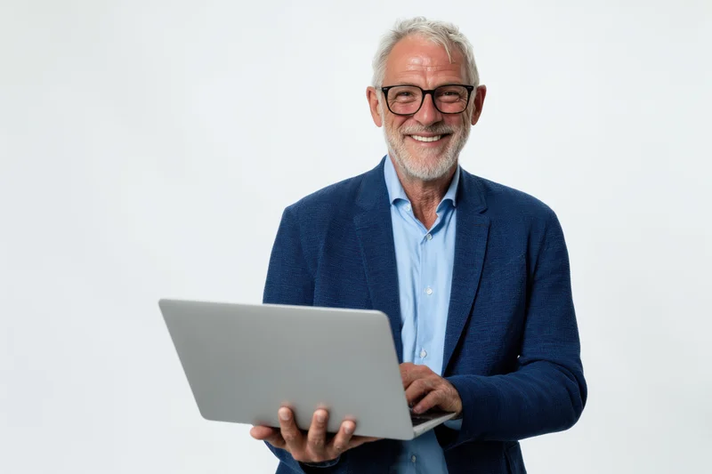 Smiling senior man in blue blazer holding laptop against white background