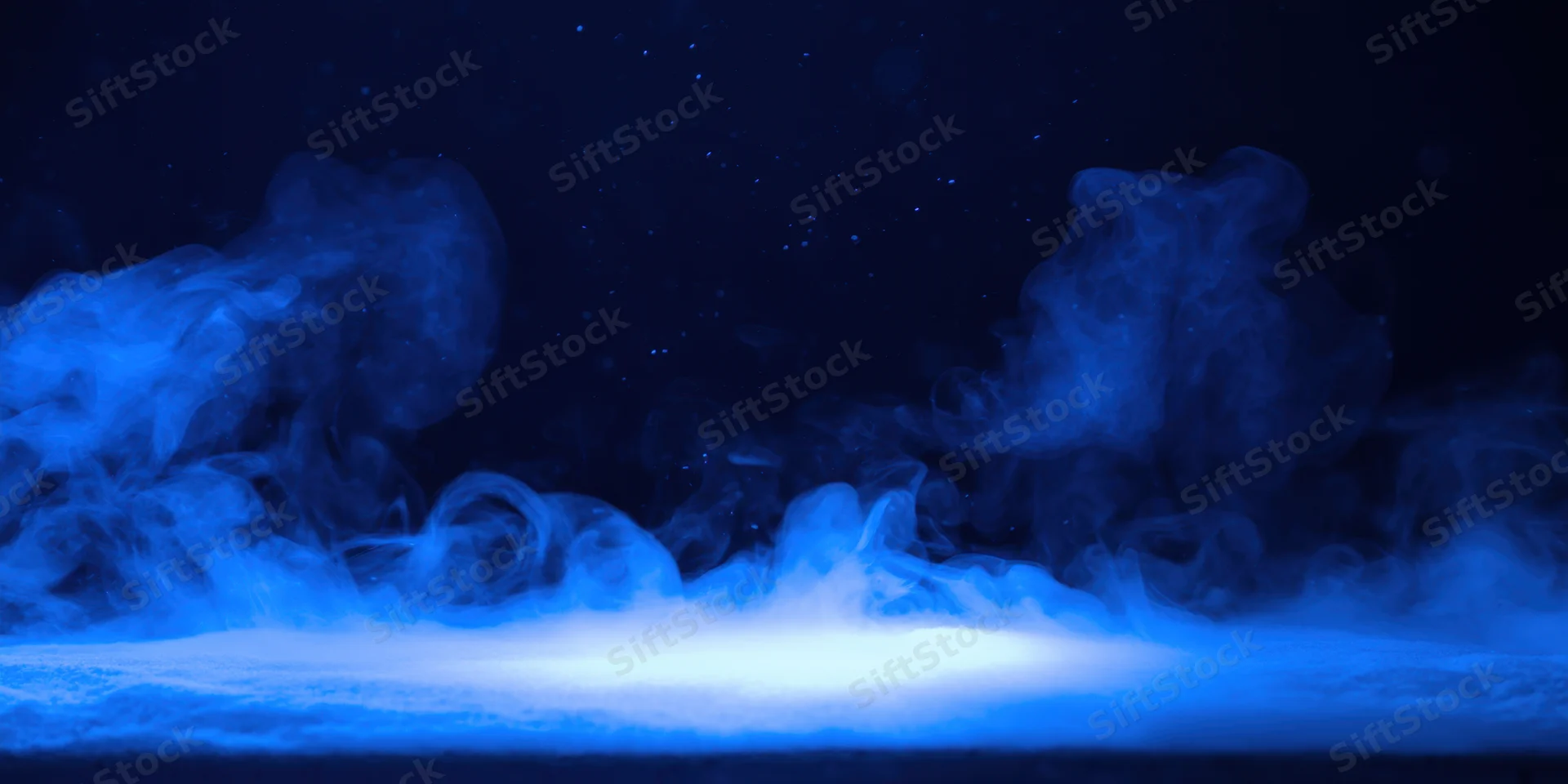 Wispy blue smoke curling above a glowing floor in a dark space