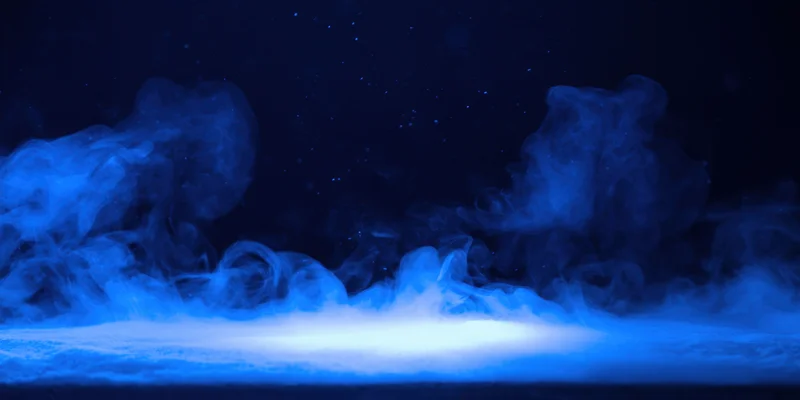 Wispy blue smoke curling above a glowing floor in a dark space