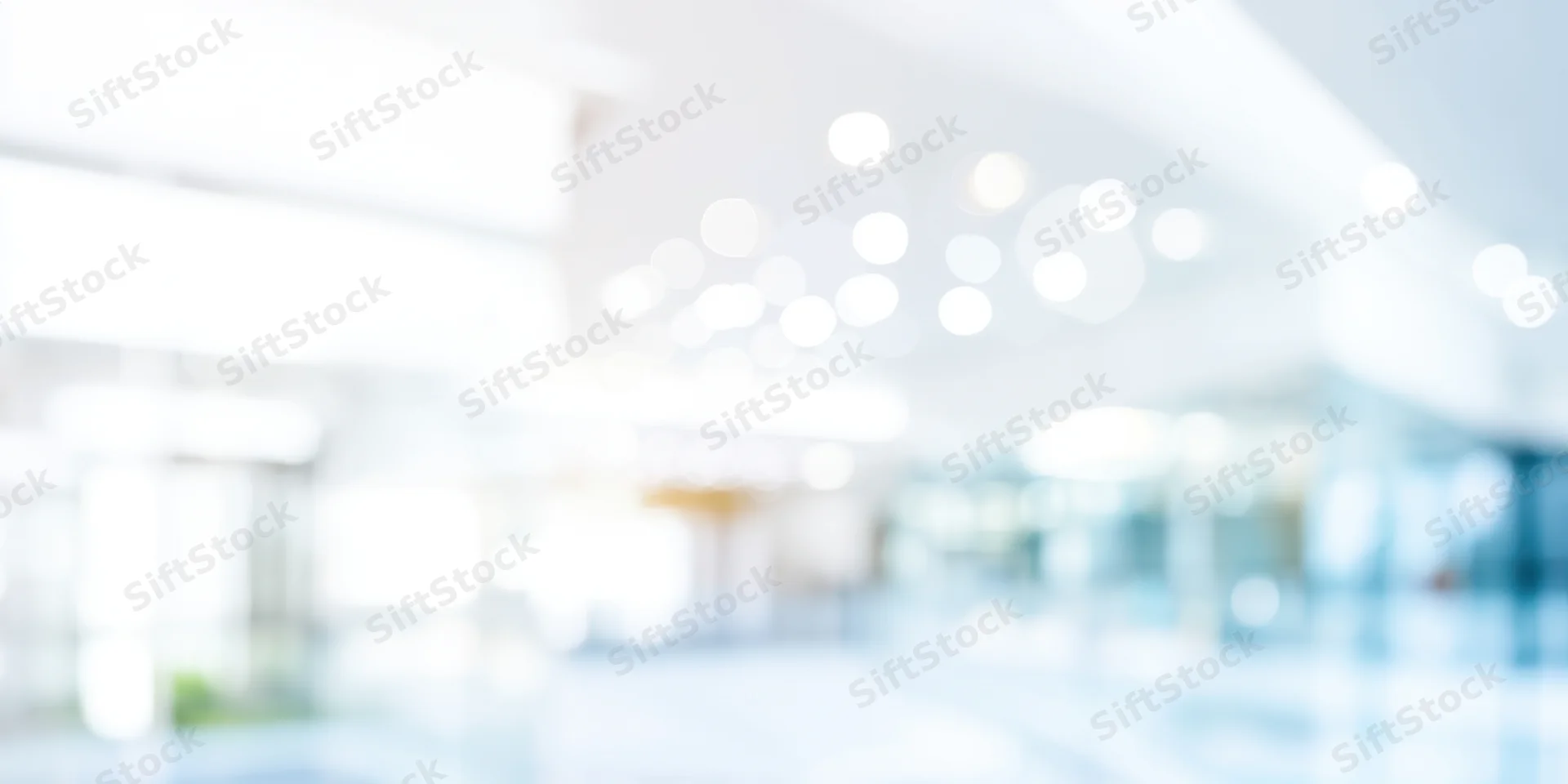 Blurred modern office interior with white walls and ceiling lights creating bokeh effect