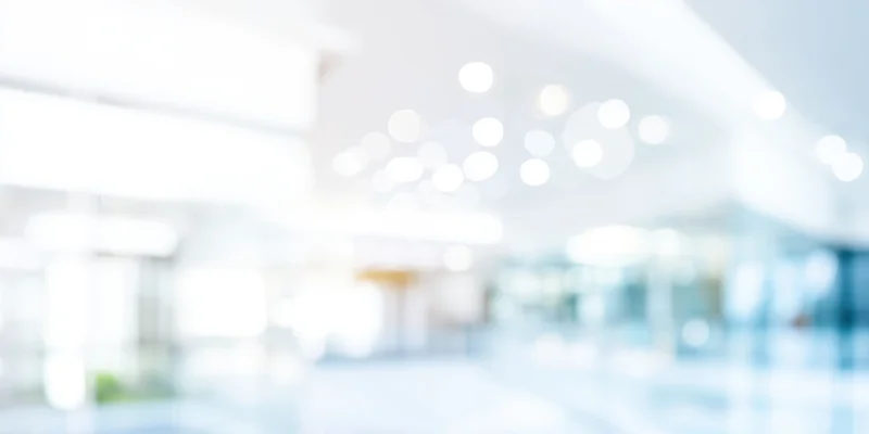 Blurred modern office interior with white walls and ceiling lights creating bokeh effect