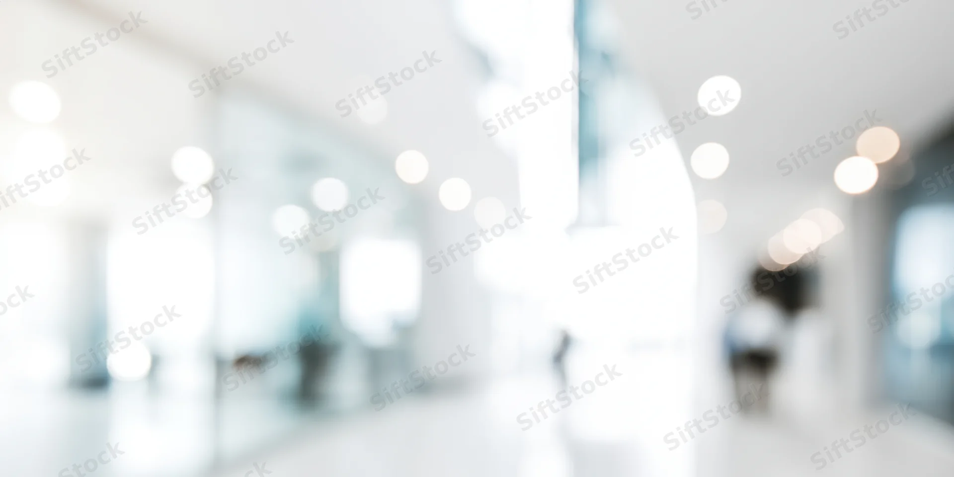 Blurred modern office hallway with white walls and ceiling lights