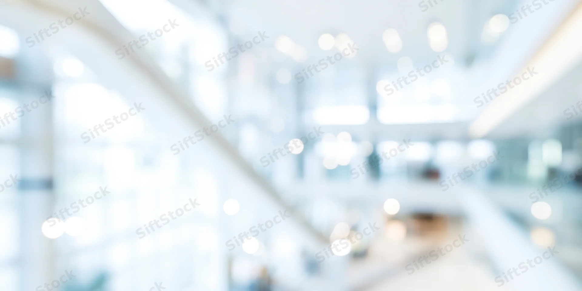 Blurred modern office lobby with white walls and glass staircase