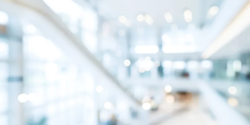 Blurred modern office lobby with white walls and glass staircase