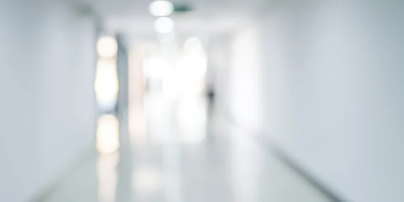 Blurred hallway with white walls and glossy floor reflecting ceiling lights
