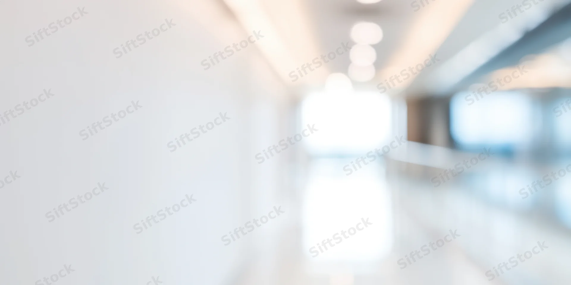 Blurred view of a bright modern office corridor with white walls and glossy floor