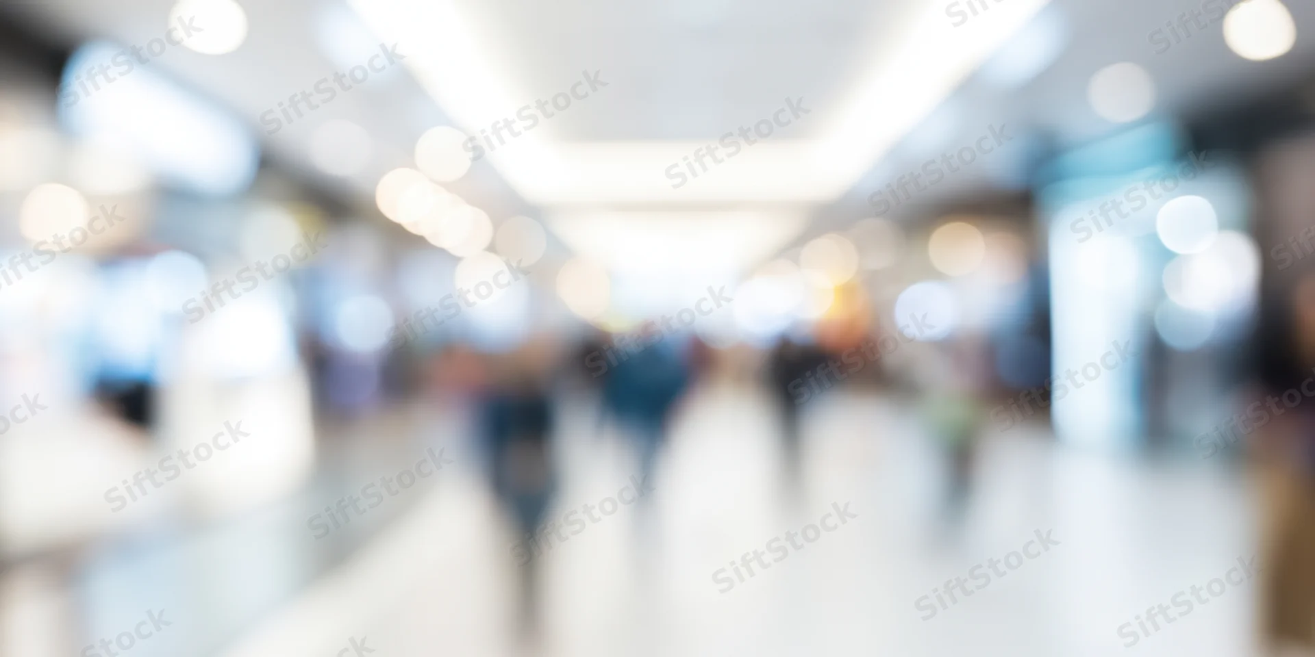 Blurred view of people walking in a bright modern shopping mall corridor
