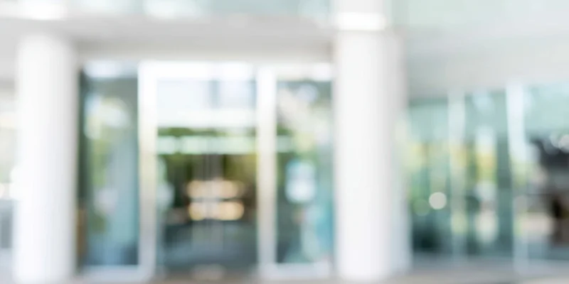 Blurred entrance to a modern glass building with white columns and bokeh lighting