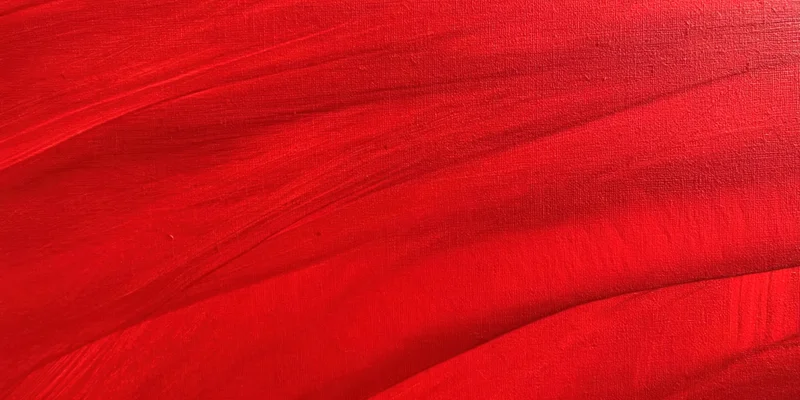 Bold red textured surface with sweeping brushstrokes in close-up view