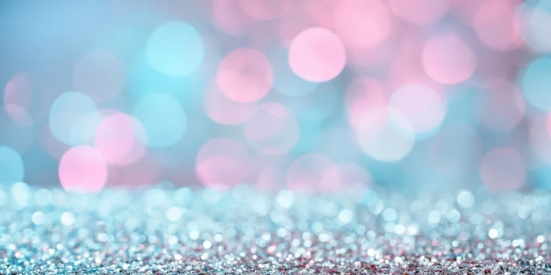 Glittering surface with tiny reflective particles under soft bokeh lighting, creating a festive abstract background with copyspace