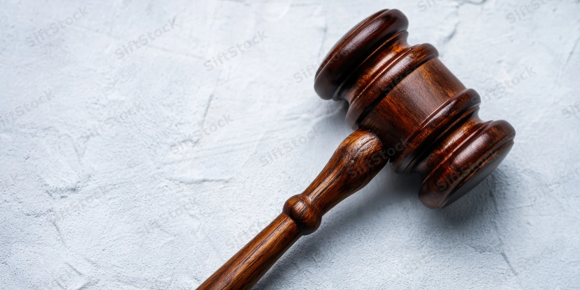 Polished wooden gavel resting on textured light gray surface