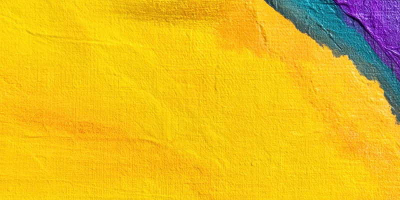 Textured canvas with bright yellow paint and colorful edges in close-up view