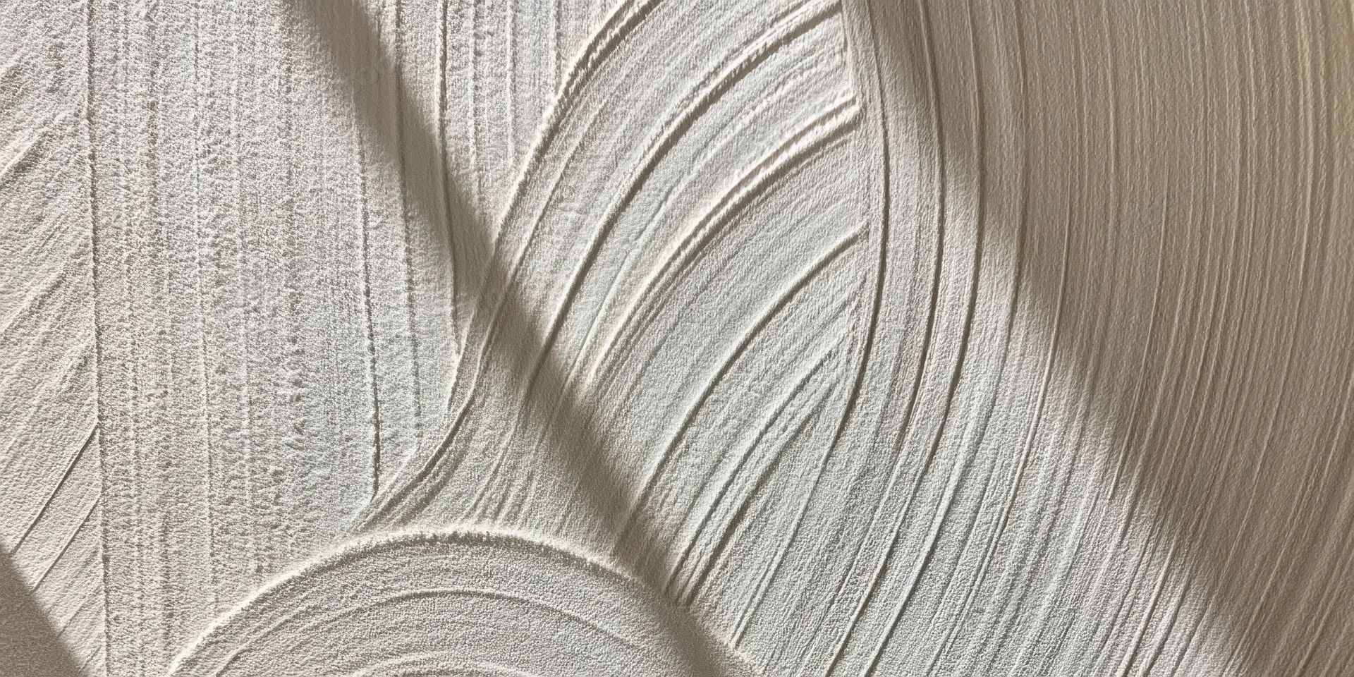 Close-up of off-white plaster surface with curved ridged texture and light shadow patterns