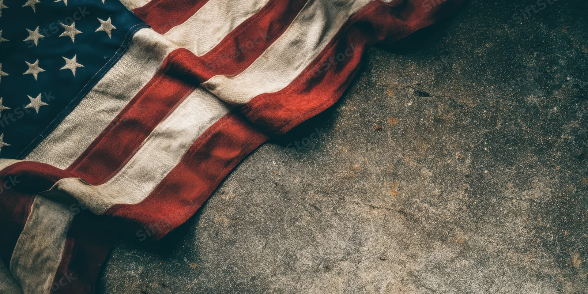 Weathered american flag lying on rough concrete surface