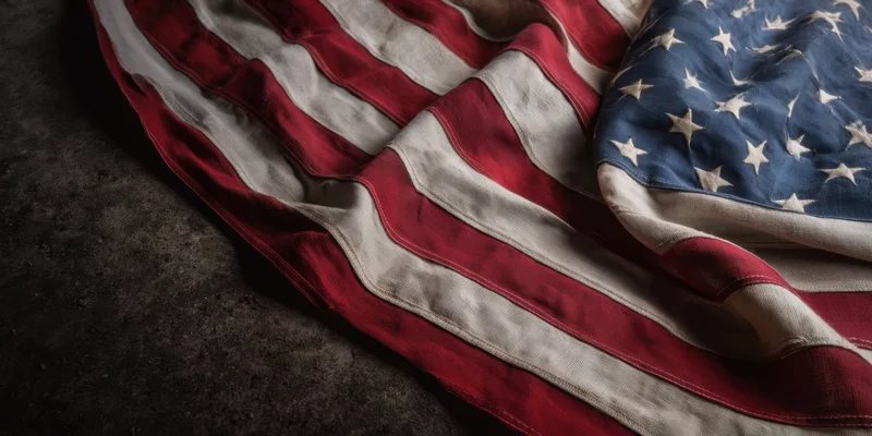 Weathered american flag draped on dark surface showing red white stripes and blue field with stars