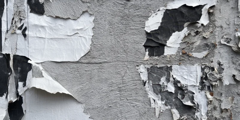 Close-up of a weathered urban wall with peeling paint and torn paper posters