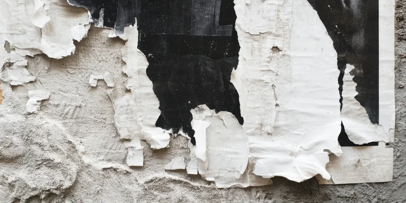 Torn posters peeling from a weathered urban wall