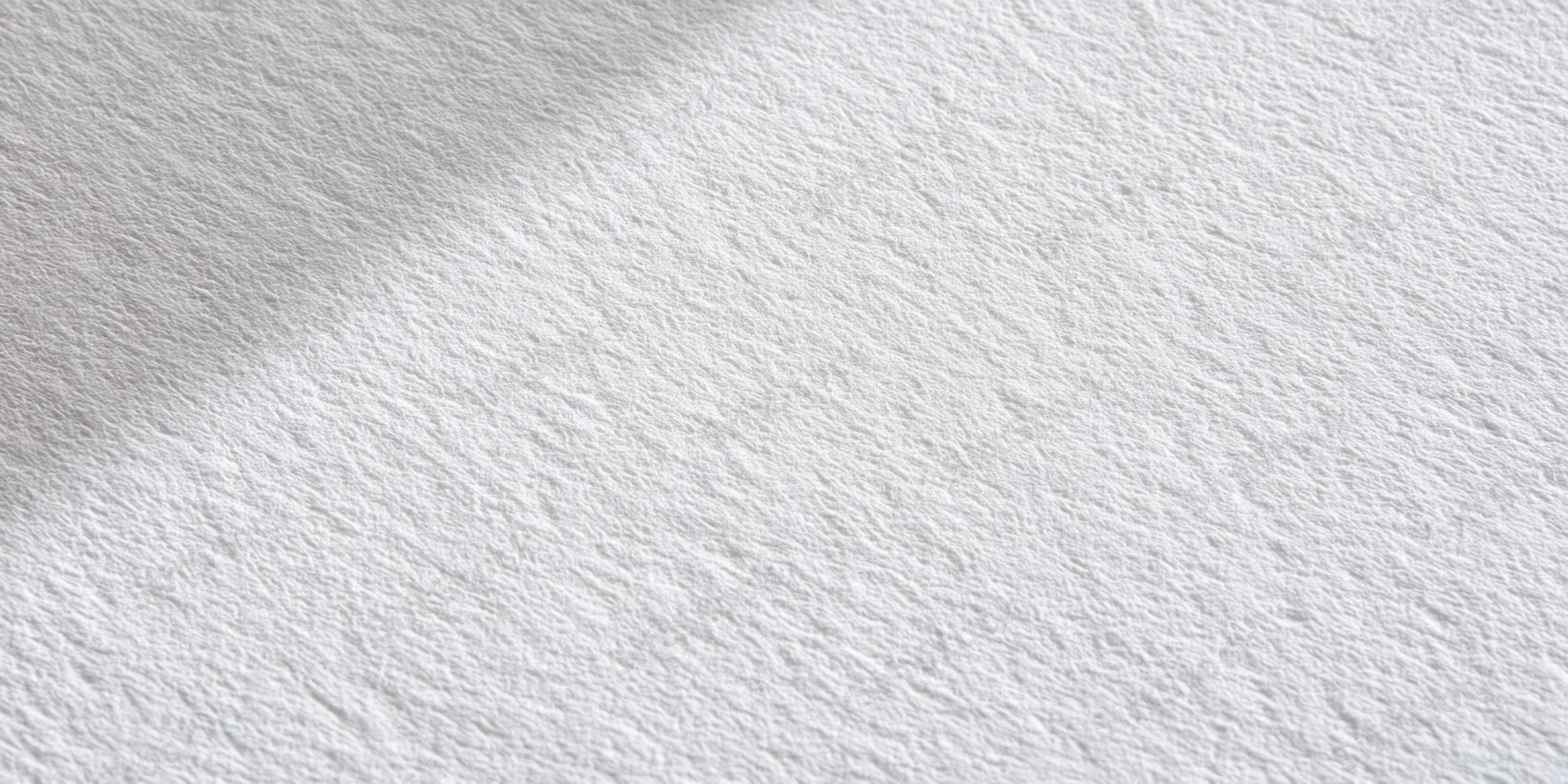 Close-up of a white textured surface with fine grain and soft shadows