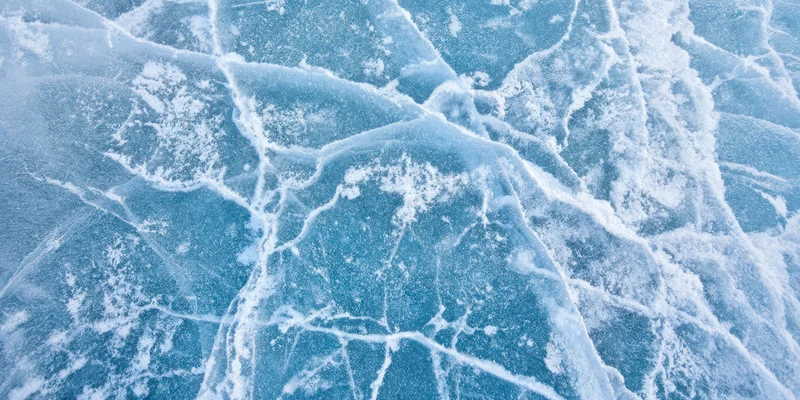 Close-up of blue ice with white cracks and frost covering its surface