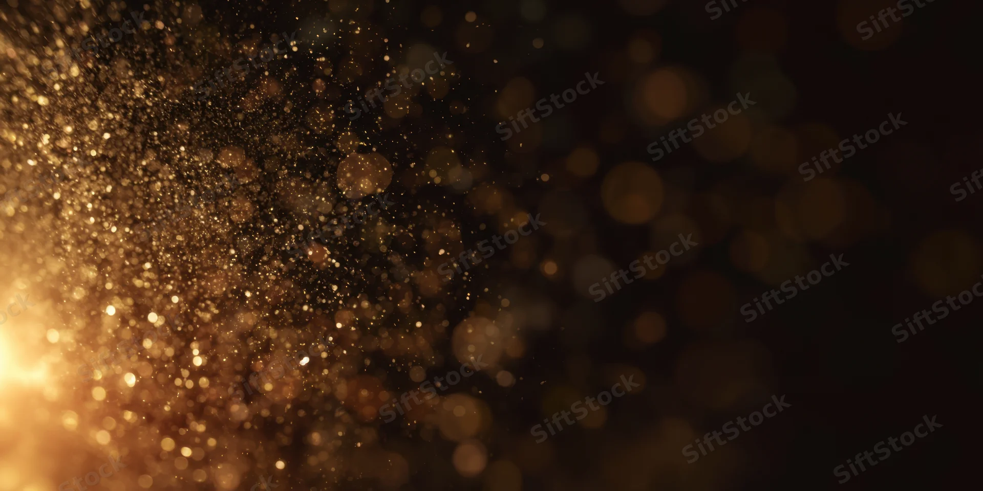 Golden dust particles floating in soft bokeh light against dark background
