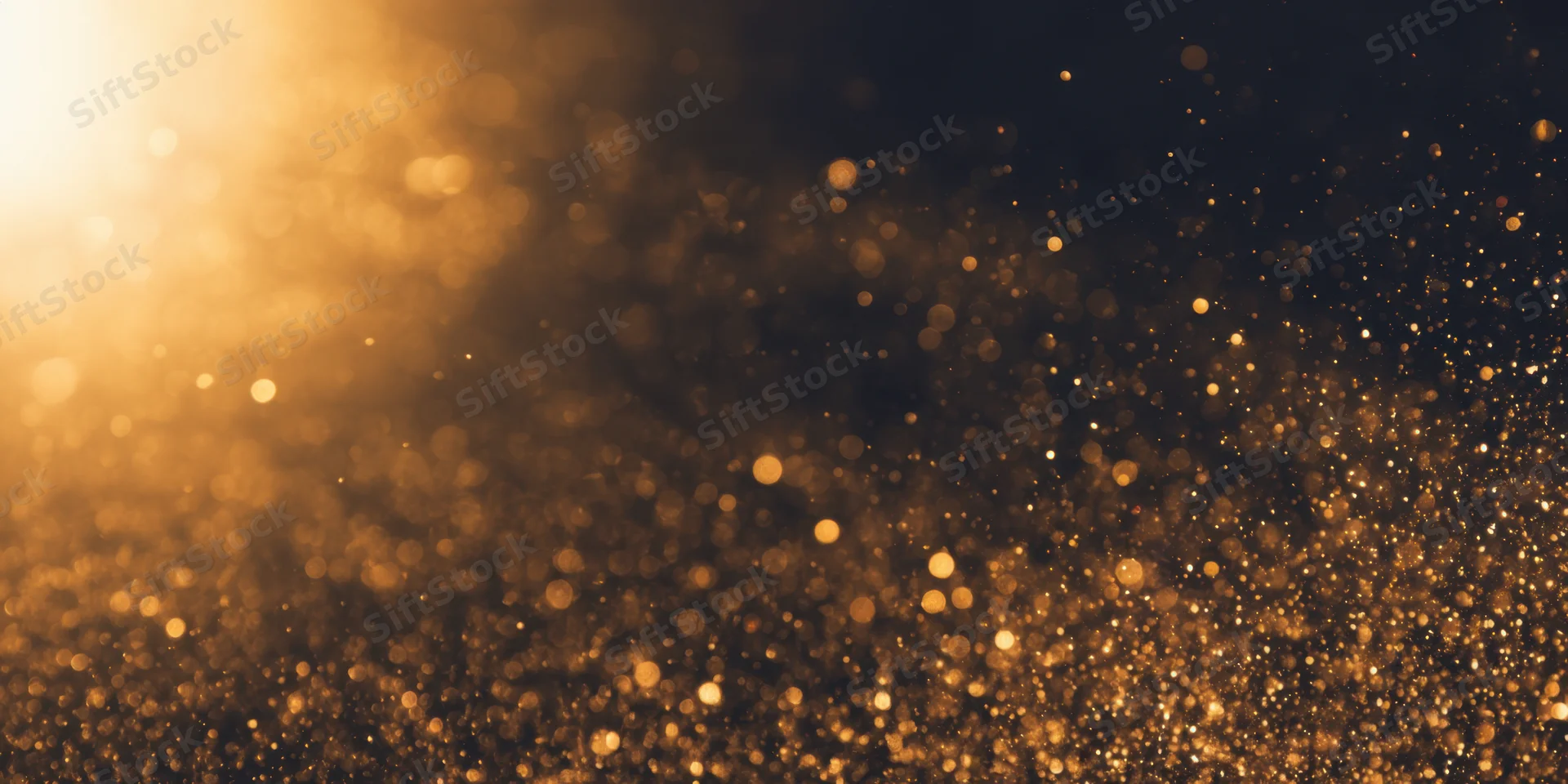 Golden dust particles floating in soft bokeh light against dark background
