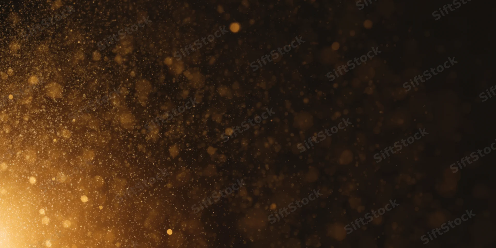 Golden dust particles floating in soft bokeh light against dark background