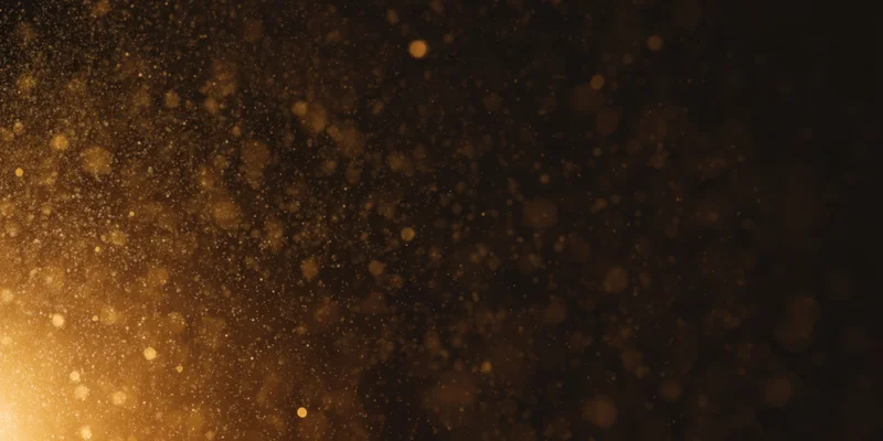 Golden dust particles floating in soft bokeh light against dark background
