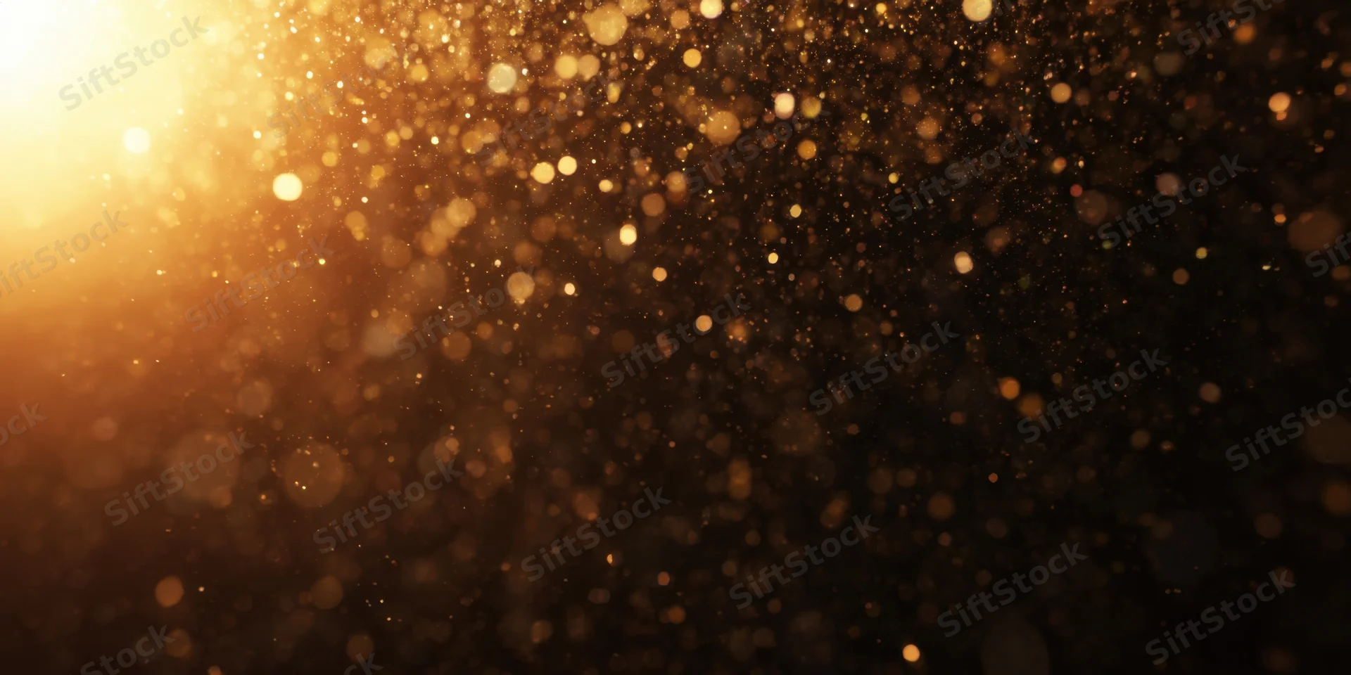 Golden dust particles floating in soft bokeh light against dark background