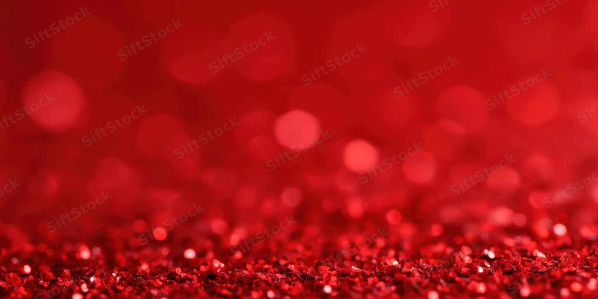 Close-up of red glitter particles with sparkling bokeh effect in the background
