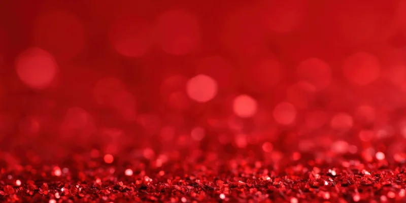 Close-up of red glitter particles with sparkling bokeh effect in the background