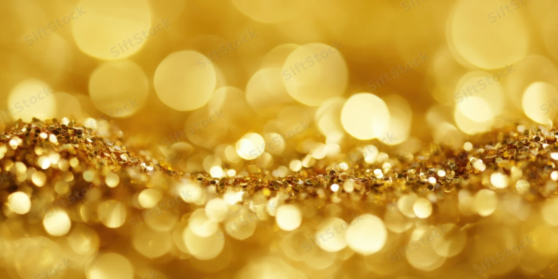 Shimmering gold glitter arranged in a wavy line with soft bokeh lights behind
