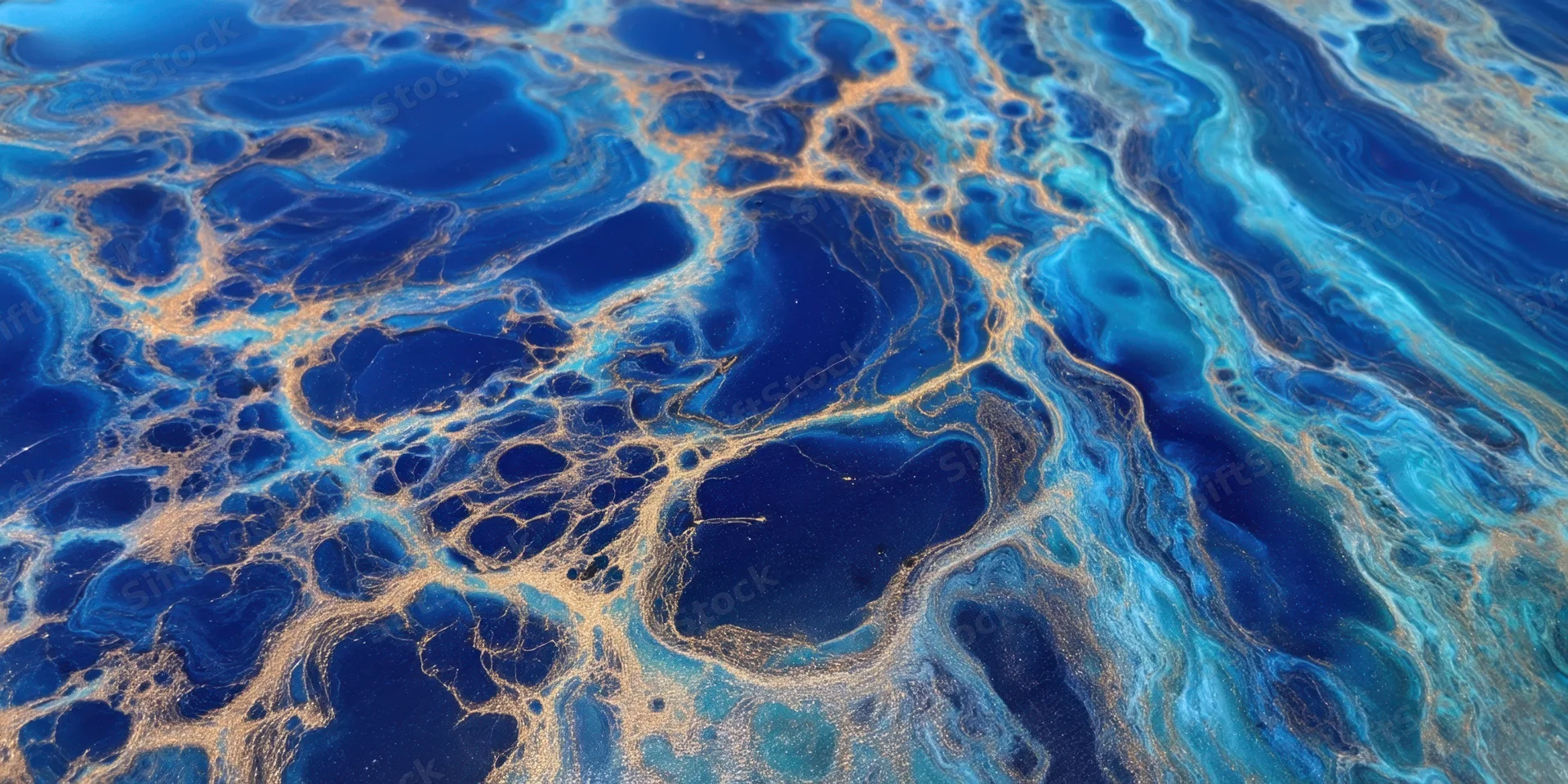 Swirling cobalt blue and turquoise marbling with gold veining across a fluid surface