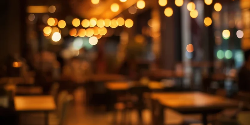 Blurred interior of a cozy cafe with warm amber lighting and tables at dusk
