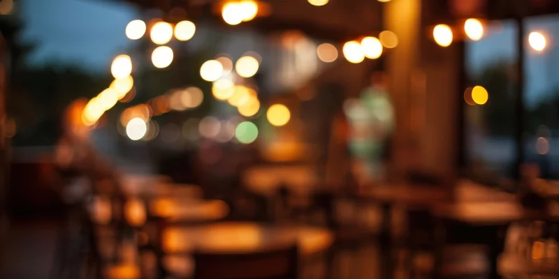 Blurred interior of a cozy cafe at dusk with warm amber lighting and bokeh effect