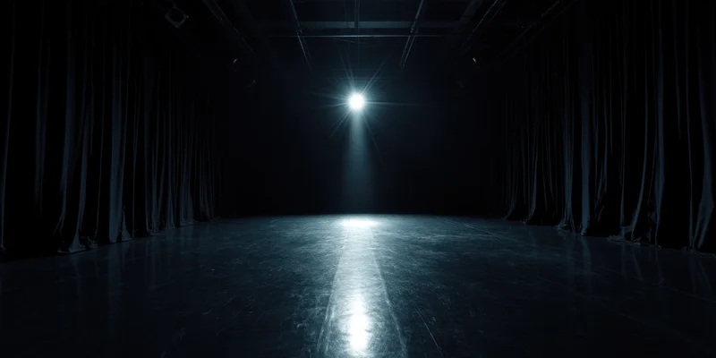 Empty stage illuminated by a single spotlight with curtains on either side