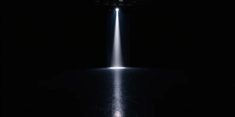 Single spotlight beam on dark empty stage floor with reflection