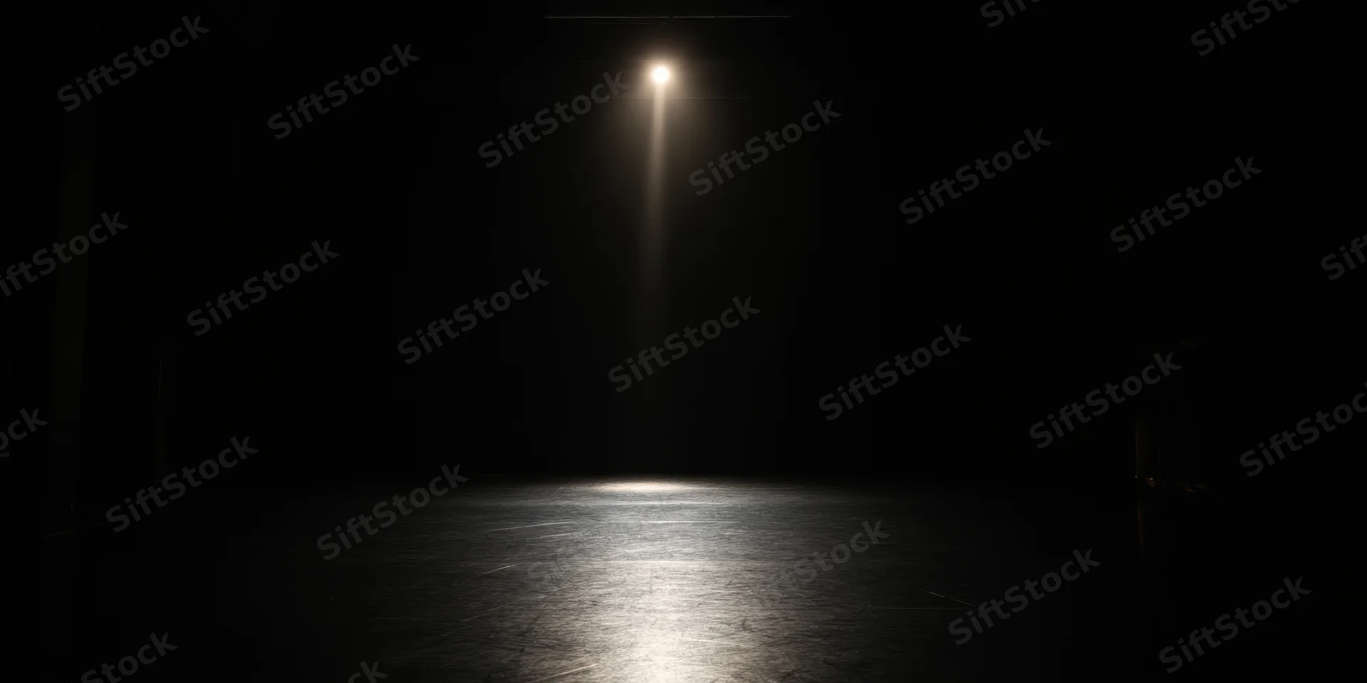 Single spotlight illuminating empty dark stage floor
