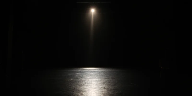 Single spotlight illuminating empty dark stage floor